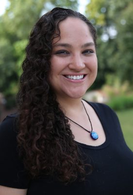 A woman with long curly hair wearing a necklace.