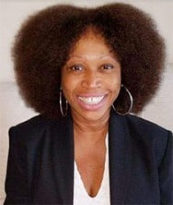 A woman with big hair is smiling for the camera.