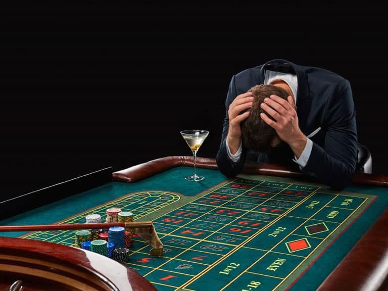 A man in suit and tie sitting at a table with roulette.